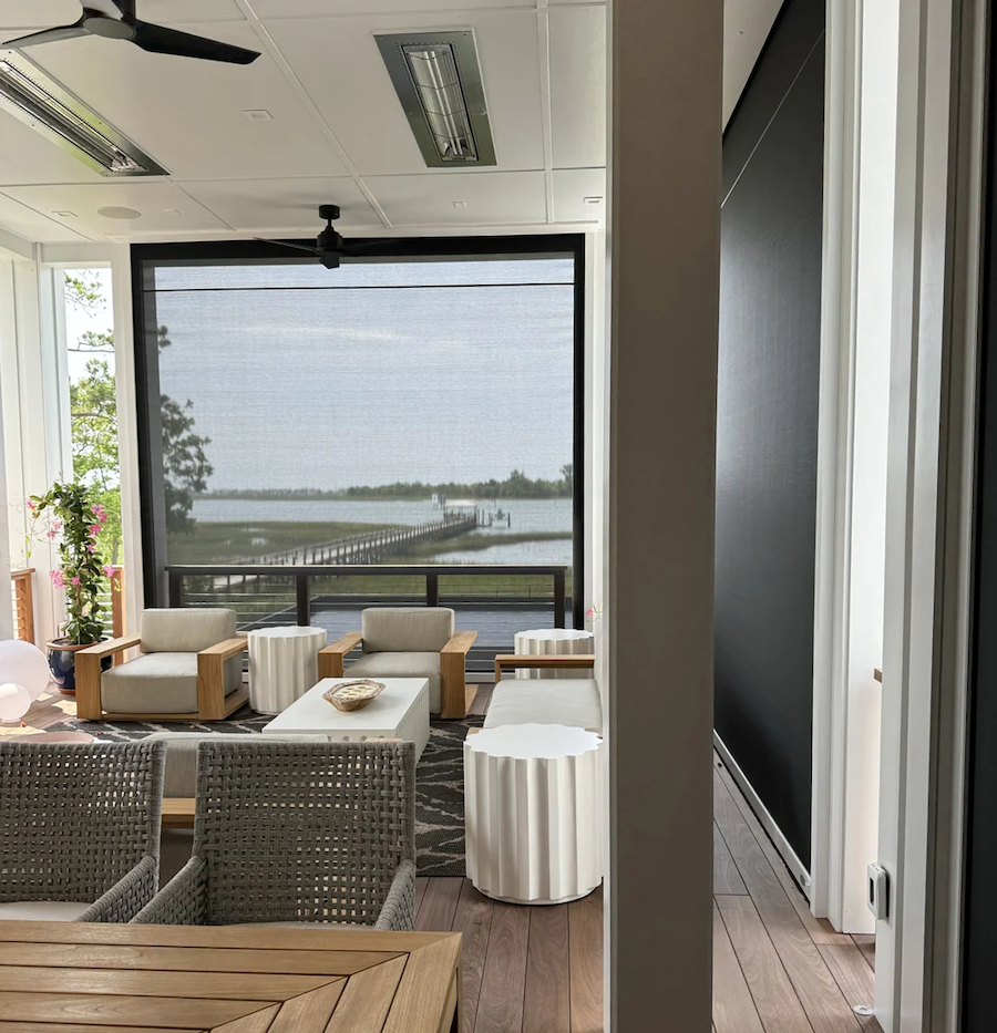 A hot tub in a window overlooking a yard, complemented by outdoor motorized shades.